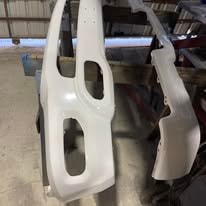 White powder coated automotive body panels hanging in the workshop