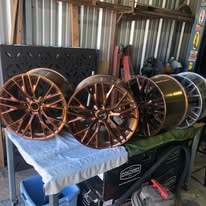 Bronze powder coated alloy wheels stacked on a table