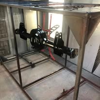 Black powder coated truck axle housing on a fabrication stand