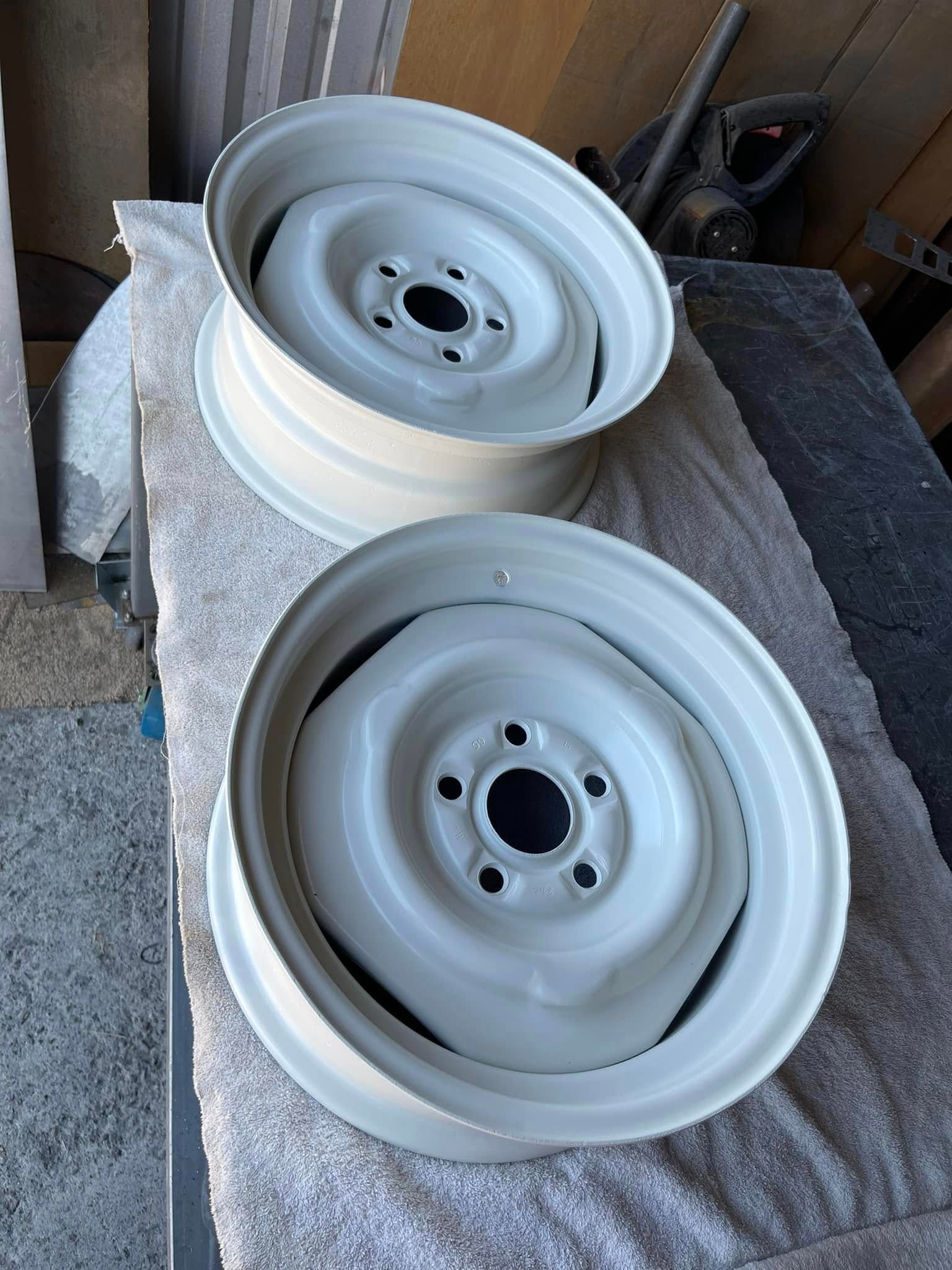 Two pale white powder coated steel wheels resting on a towel