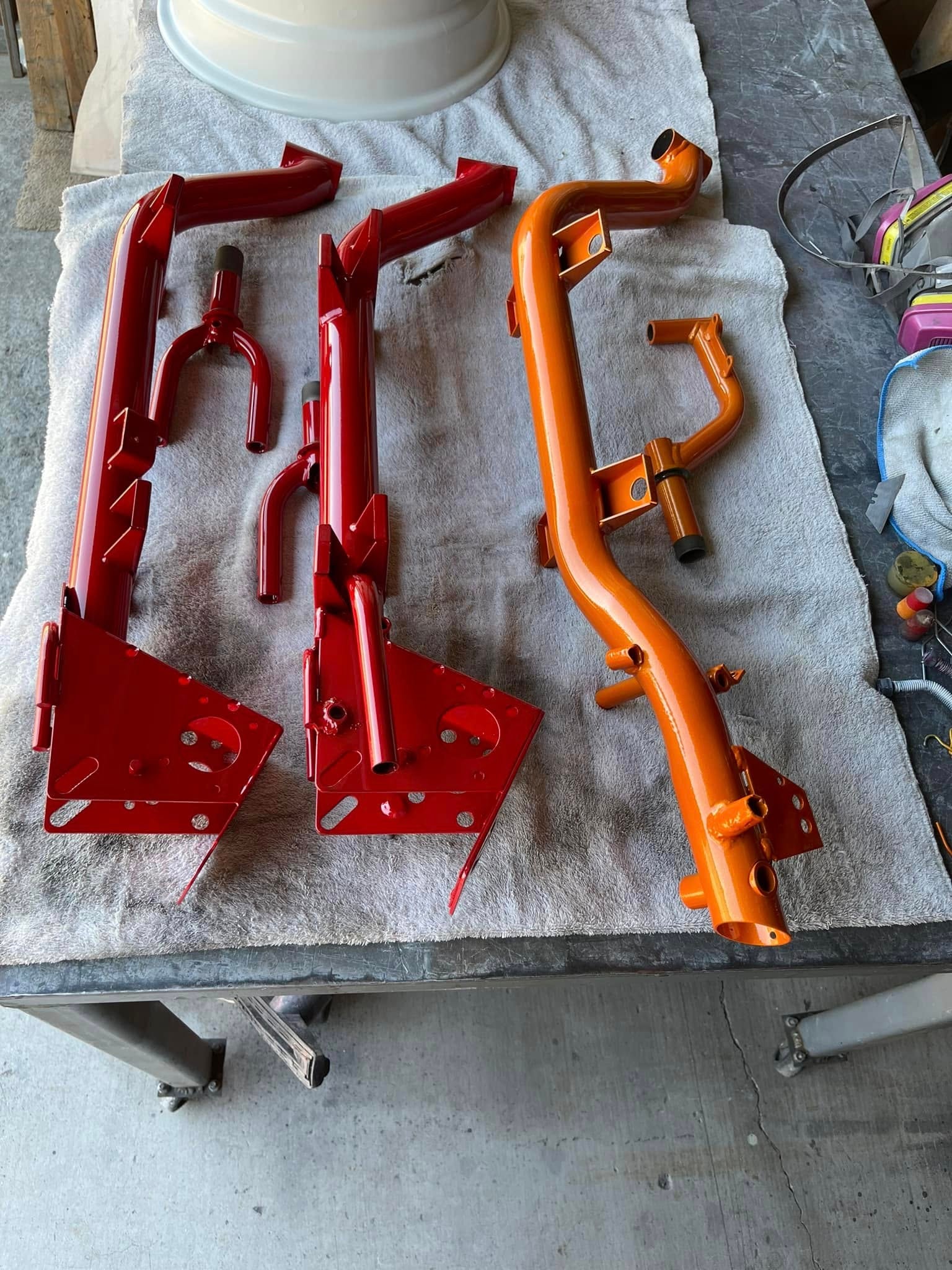 Red and orange powder coated tube frames laid on a towel