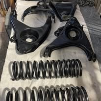 Black powder coated control arms and coil springs on a drop cloth